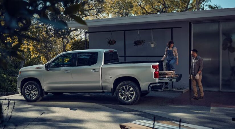 A man and a woman are shown loading a silver 2023 Chevy Silverado 1500 Z71 during a 2023 Chevy Silverado 1500 vs 2023 Ford F-150 comparison.