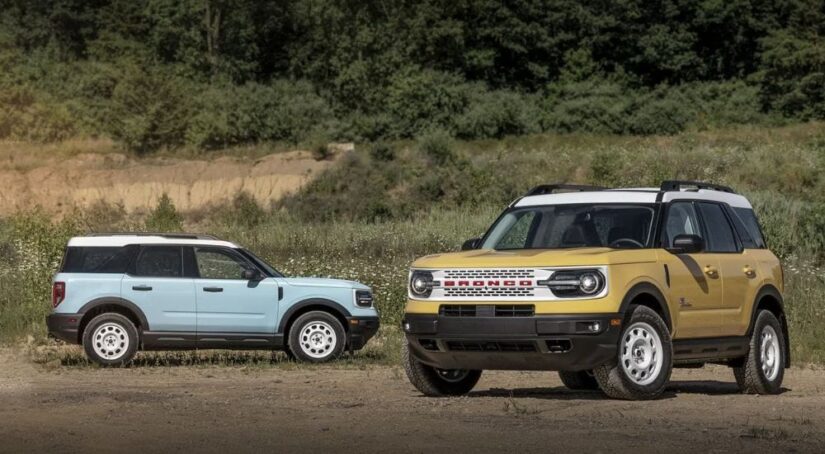 A Robin Egg's Blue 2023 Ford Bronco Sport Heritage Edition and a yellow Heritage Limited Edition are shown parked in a field.