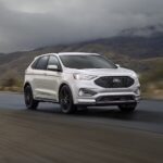 A white 2023 Ford Edge is shown cruising down the highway.