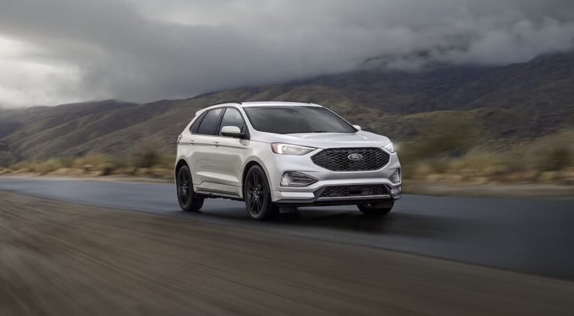 A white 2023 Ford Edge is shown cruising down the highway.