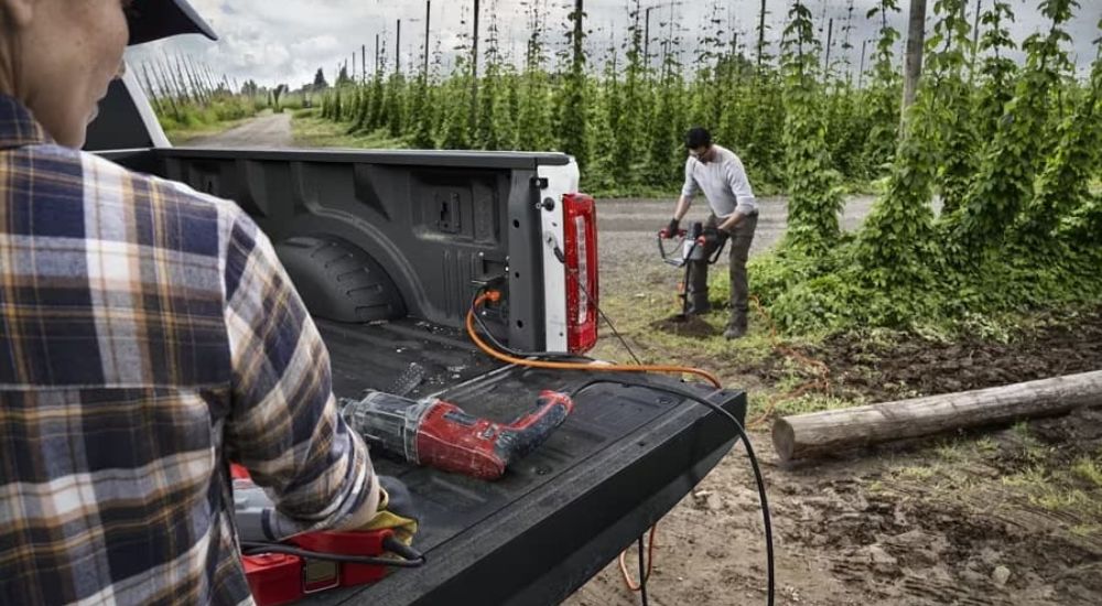 Two men work with power tools plugged into the Pro Power Onboard cargo box outlets. 