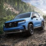 A blue 2023 Honda Pilot is shown descending on a rocky slope.