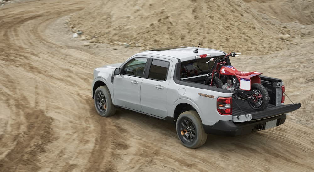 A grey 2023 Ford Maverick Tremor is shown from the rear while loaded with a dirt bike.