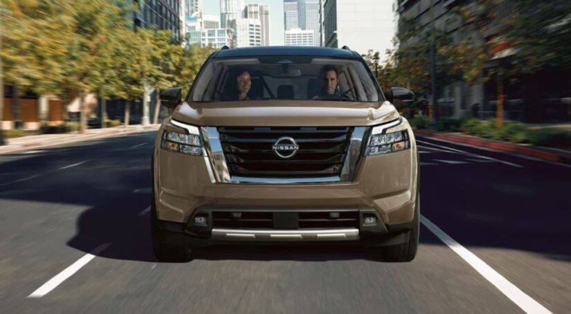 A tan 2023 Nissan Pathfinder is shown driving on a street after winning a 2023 Nissan Pathfinder vs 2023 Kia Sorento comparison.