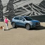 A blue 2023 Toyota Corolla Cross is shown parked in front of a mural.