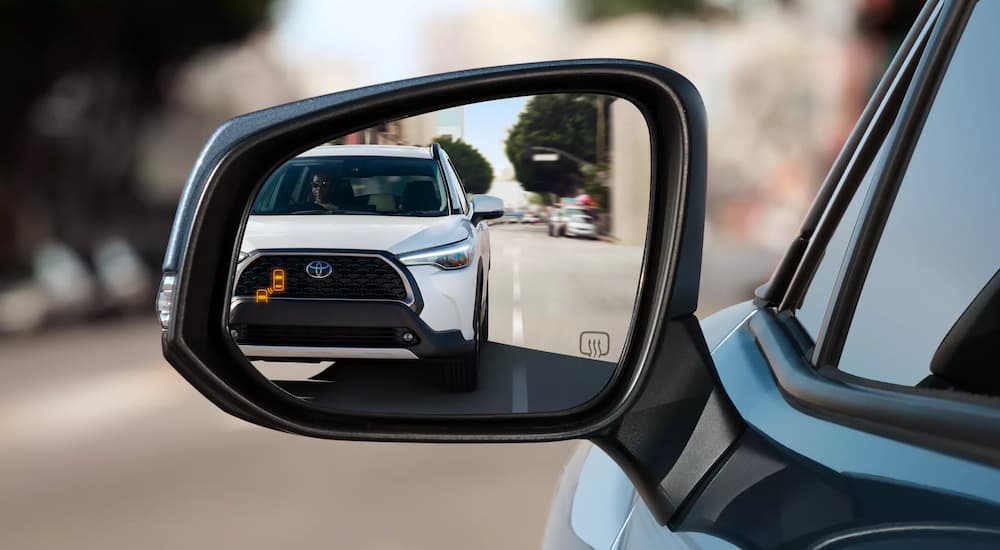 A white 2023 Toyota Corolla Cross XLE is shown in a car mirror.