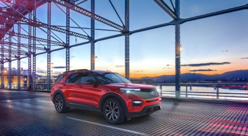 A red 2023 Ford Explorer ST is shown from the side while driving over a bridge.