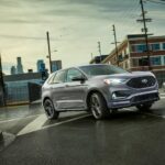 A grey 2022 Ford Edge ST is shown from the front at an angle on a city street.
