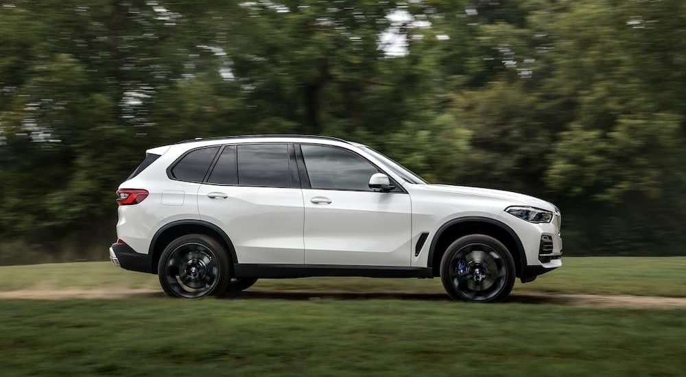 A white 2018 BMW X5 is shown driving on a dirt road.