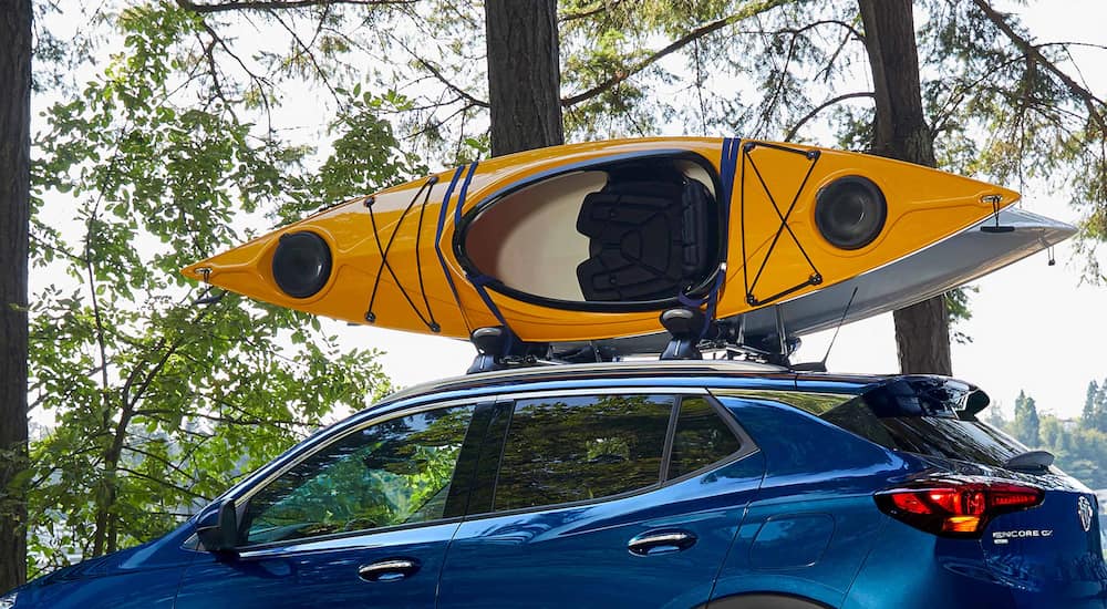 A close up of a kayak on the roof of a blue 2023 Buick Encore GX is shown.