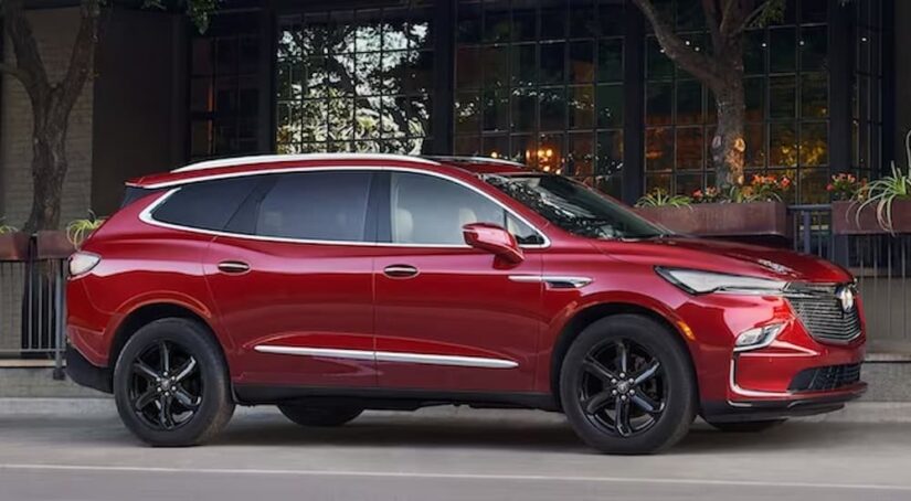 A red 2023 Buick Enclave for sale is shown parked on a city street.