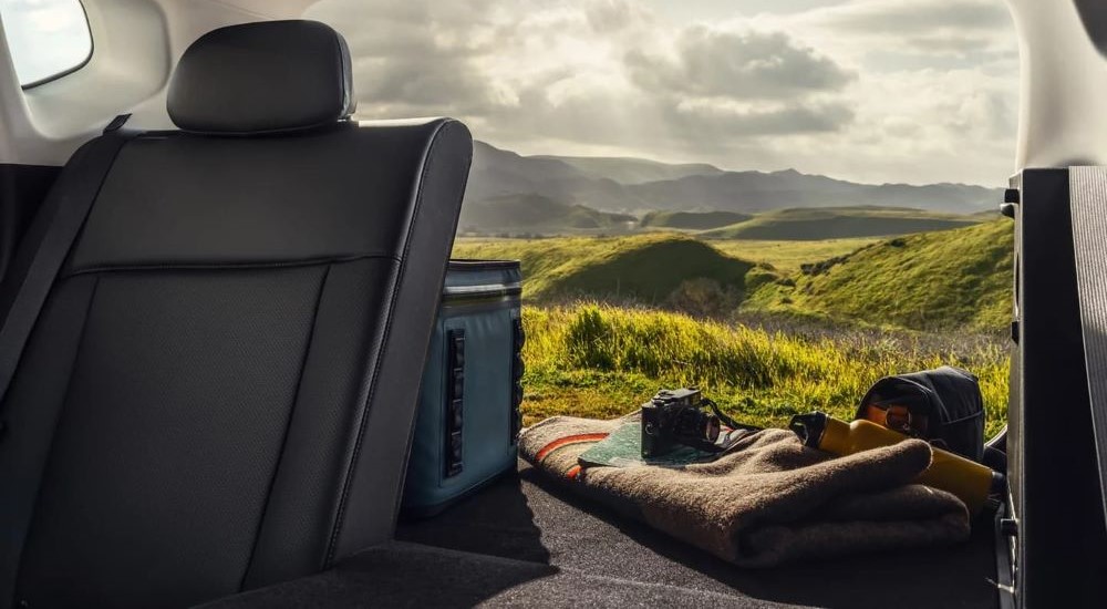 The rear folded seats and picnic items are shown in the trunk of a 2024 Hyundai Kona.