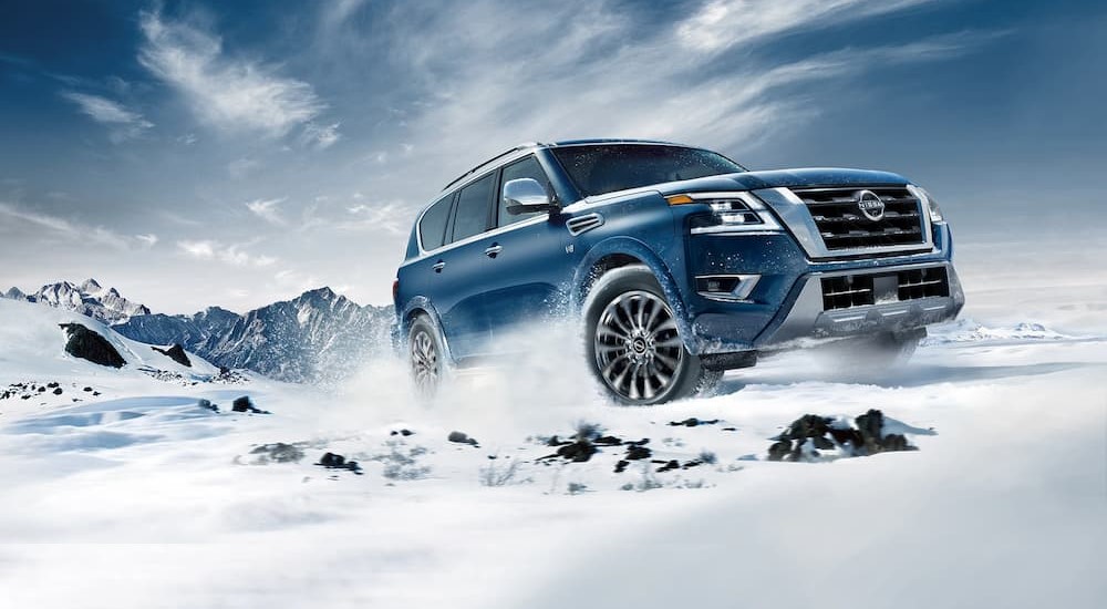 A 2023 blue Nissan Armada Platinum V8 is shown driving on the snow.