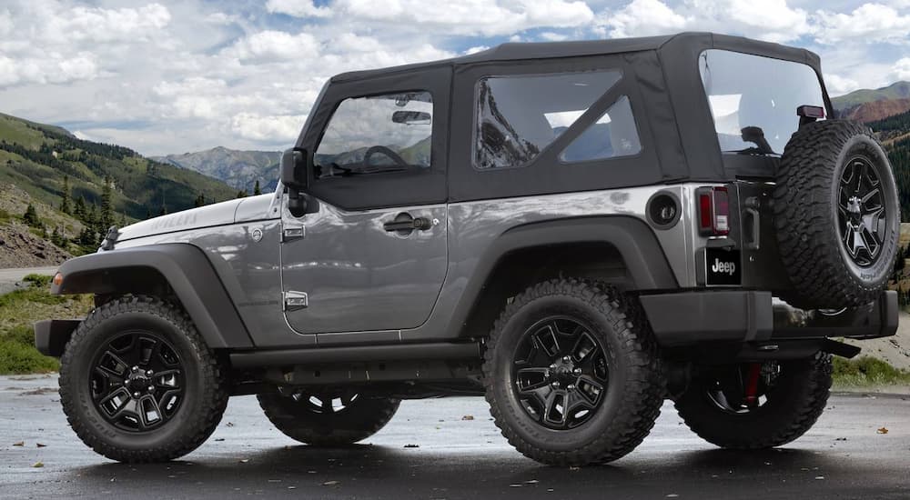 A silver 2017 Jeep Wrangler Willys is shown parked with mountains in the background.