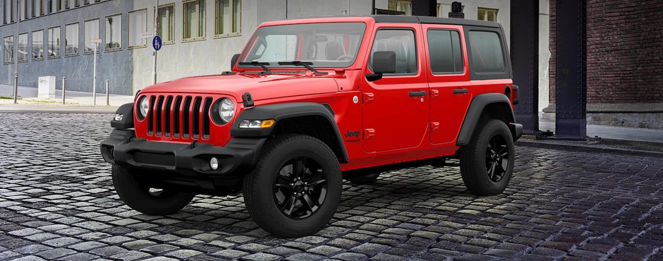 A red 2021 used Jeep Wrangler for sale is shown in a parking lot.