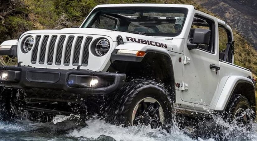 A white 2018 Jeep Wrangler Rubicon is shown splashing through a mountain creek.