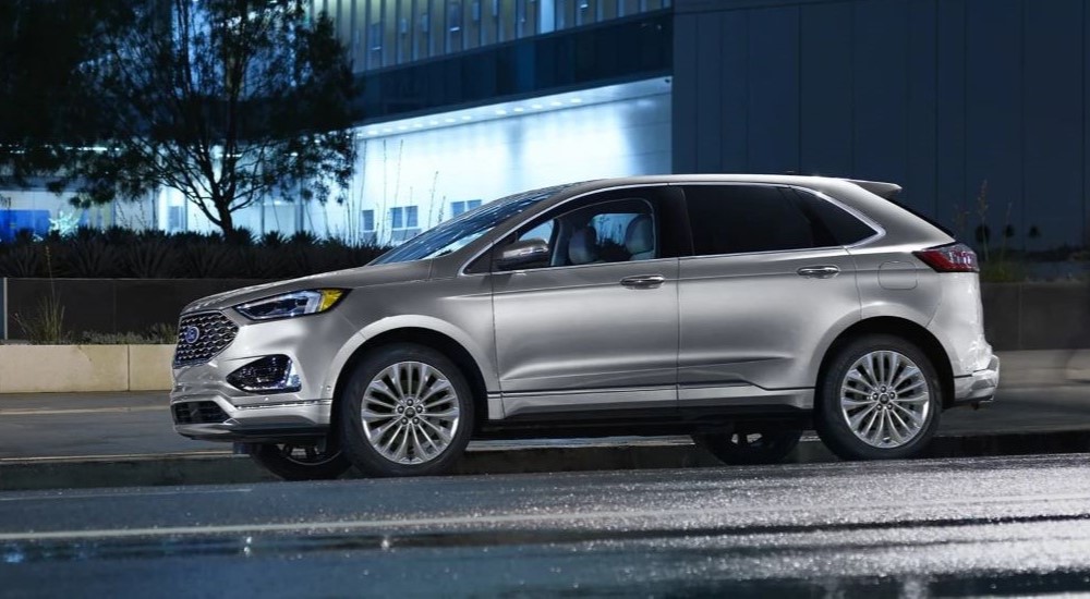 A silver 2023 Ford Edge ST is shown parked on a street near a building.