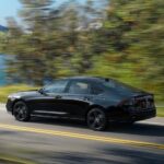A black 2023 Honda Accord Sport-L Hybrid is shown driving on a highway near a lake.