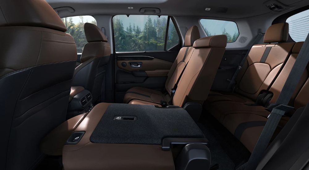 The brown interior of the 2023 Honda Pilot is shown with one of the second row seats folded flat.