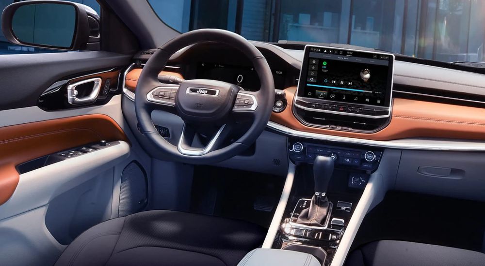 The interior of the 2023 Jeep Compass is shown with gray seats and a warm tan colored leather dash. 
