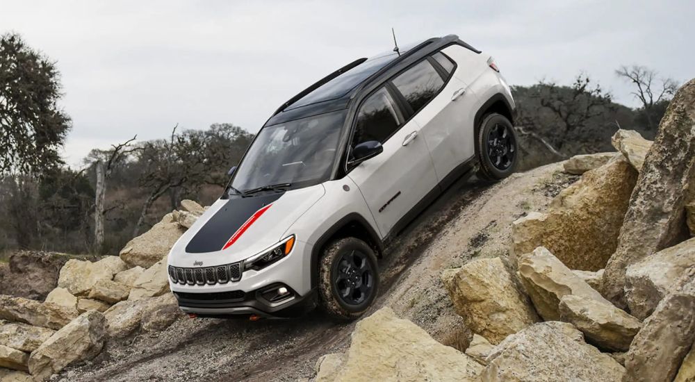 A 2023 Jeep Compass is shown driving down a steep, rocky hill.