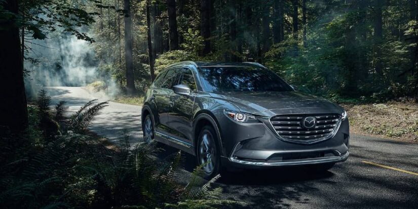 A gray 2023 Mazda CX-9 is shown driving on a road after winning a 2023 Mazda CX-9 vs 2023 Acura MDX comparison.