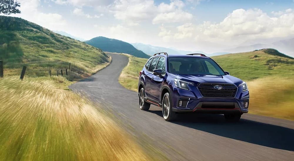 A purple 2023 Subaru Forester is shown driving on a road.