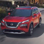 A red 2023 Nissan Rogue is shown driving after winning a 2023 Nissan Rogue vs 2023 Subaru Forester comparison.