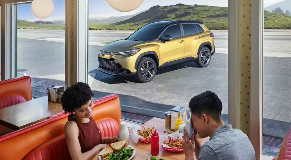 A yellow 2023 Toyota Corolla Cross is shown parked near a diner.