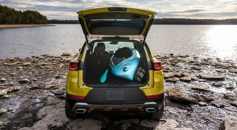 The cargo area of a yellow 2024 Chevy Trailblazer is shown holding a blue kayak.