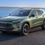 A green 2024 Chevy Trax is shown parked in front of a lake.