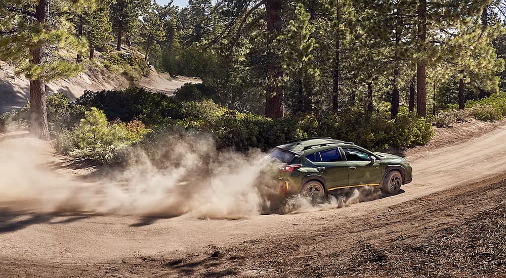 A green 2024 Subaru Crosstrek barrels down a dusty road.