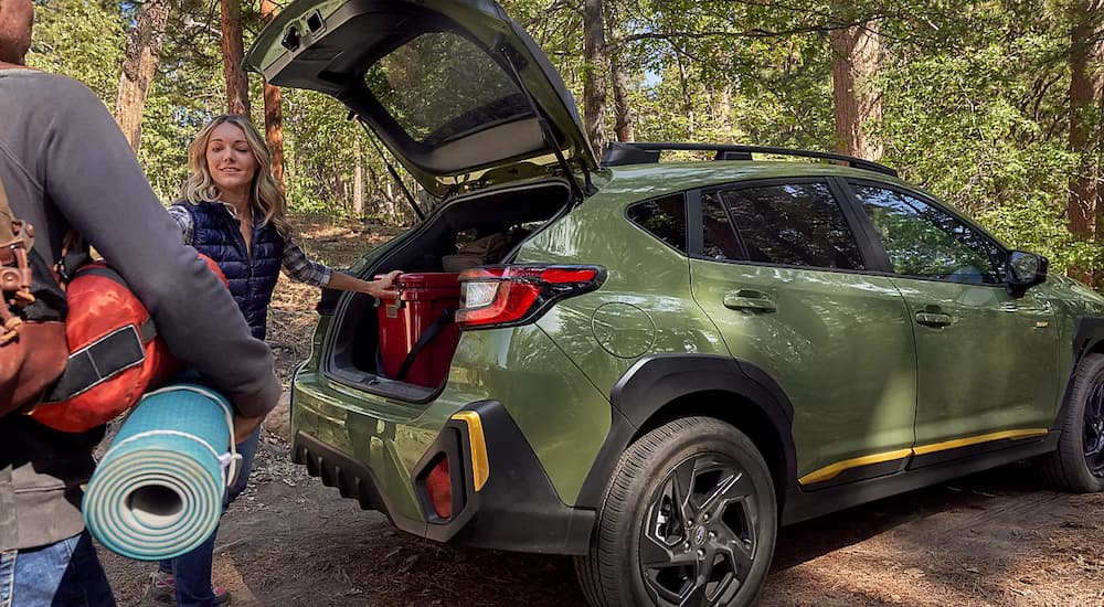Hikers are shown loading up the trunk of a green 2024 Subaru Crosstrek.