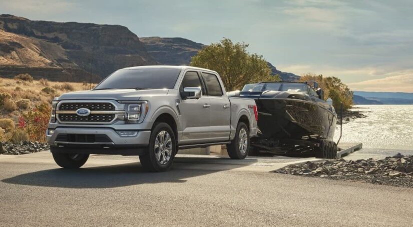 A silver 2023 Ford F-150 is shown towing a boat.