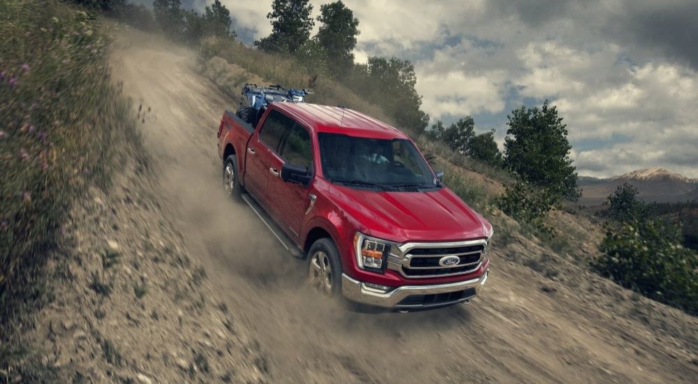 A red 2023 Ford F-150 is shown off-roading.