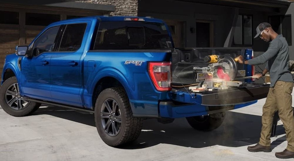 A blue 2023 Ford F-150 Sport is shown parked on a construction site.
