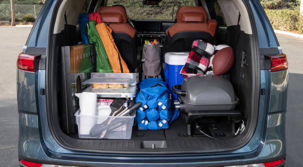 The cargo area of a 2023 Kia Carnival is shown loaded with camping supplies.