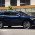 A blue 2023 Lexus RX is shown driving on a street after visiting a Lexus dealer.