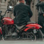 Two individuals are shown next to a red 2023 Harley Davidson Street Bob 114.