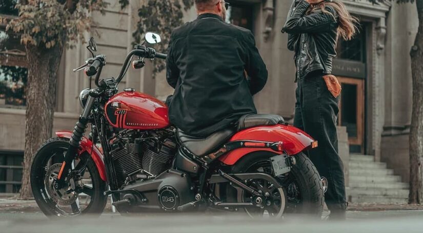 Two individuals are shown next to a red 2023 Harley Davidson Street Bob 114.