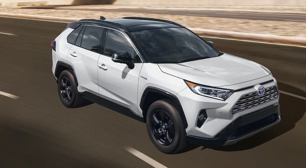 A white 2021 Toyota RAV4 Hybrid is shown driving on a highway.
