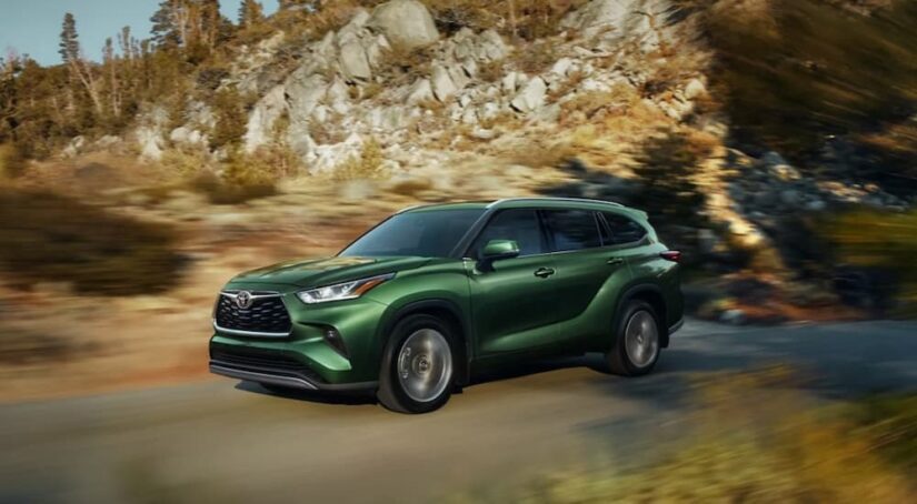 A green 2023 Toyota Highlander is shown driving after visiting a Toyota dealer.