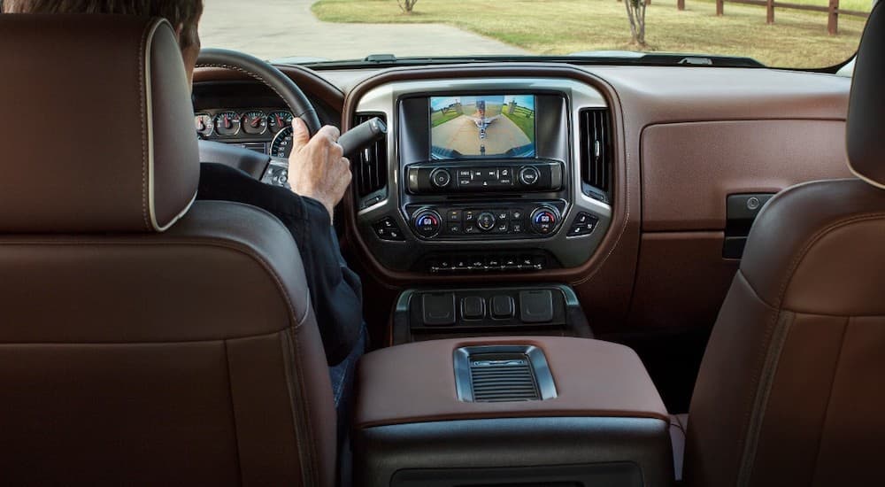 The interior of the 2018 Chevy Silverado 1500 is shown with brown leather seats from the perspective of the second row.