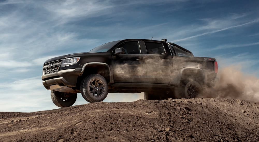 A black 2020 Chevy Colorado ZR2, one of many used trucks for sale, is shown driving off-road in dirt.