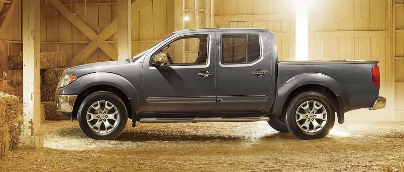 A gray 2022 Nissan Frontier is shown from the side parked in a barn.