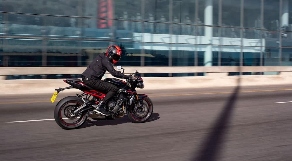A popular used Triumph for sale, a 2024 Triumph Street Triple R is shown driving on a highway.