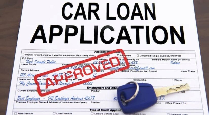 An approved car loan application is shown at a used car dealership.