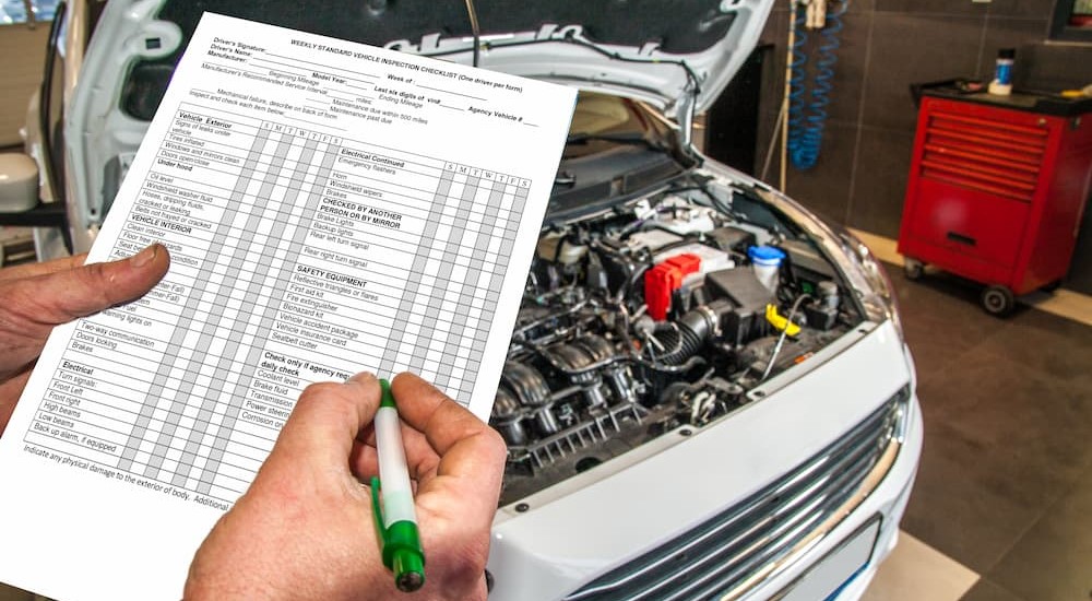A person is shown holding a vehicle inspection check list.