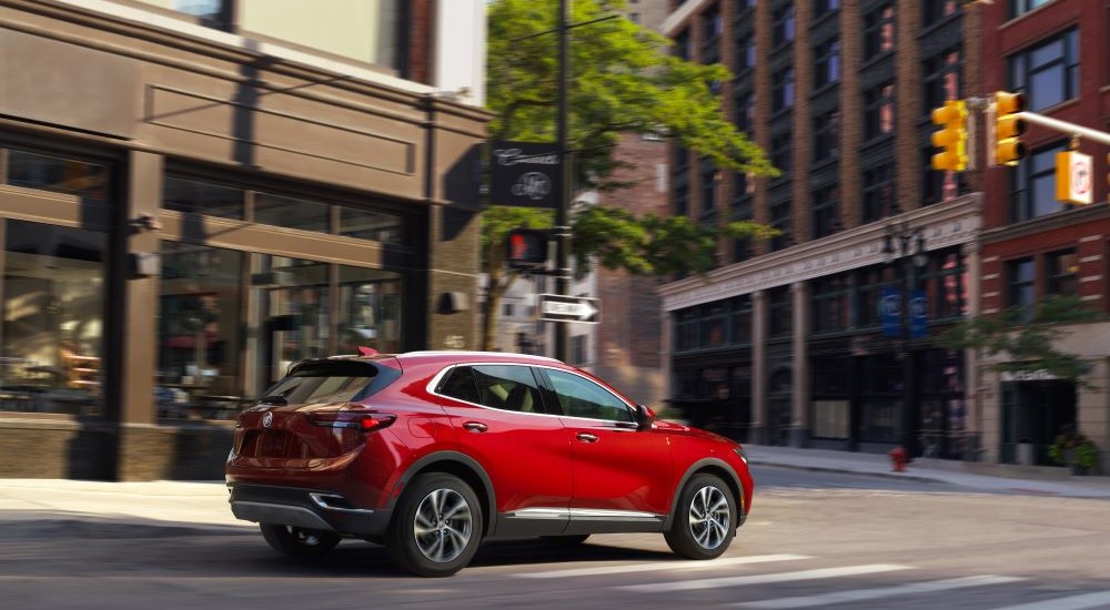 A red 2023 Buick Envision is shown driving on a city street.
