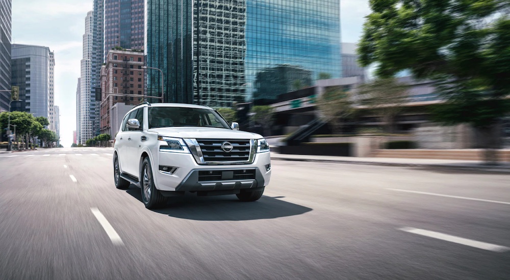 A white 2023 Nissan Armada is shown driving on a city street.